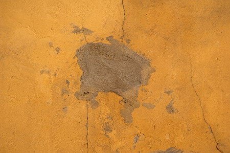 Texture of old rustic wall covered with yellow stuccoの写真素材