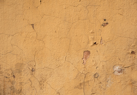 Texture of old rustic wall covered with yellow stuccoの写真素材