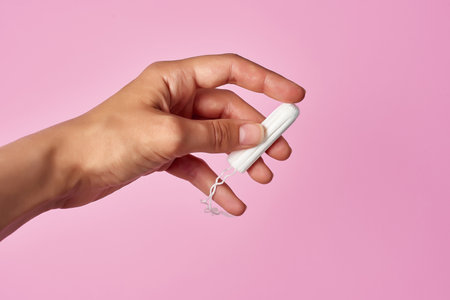 hygienic tampon in a female hand on pink backgroundの写真素材