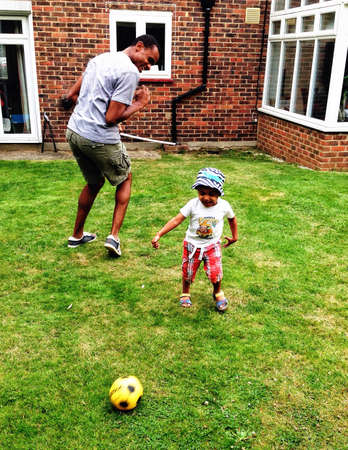 Dad and boy playing football in gardenの素材
