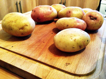 Potatoes on wooden chopping boardの素材
