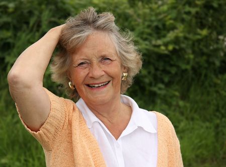Smiling lady in her sixties, outside in the garden