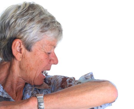 Elderly woman sneezing into her sleeve. Stop the spread of germs!の写真素材