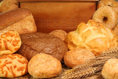 Bread box surrounded by bread and buns. 