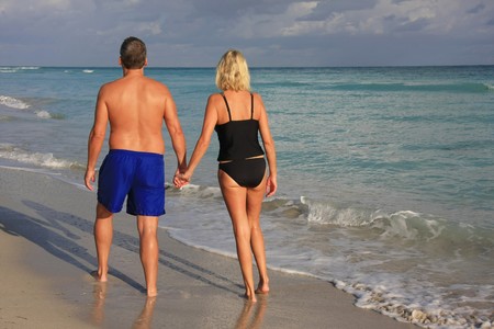 Couple holding hands, walking on the beach. の写真素材