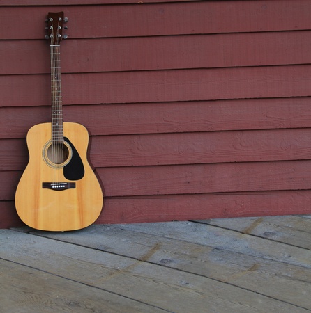 Acoustic guitar against an old plank wall. の写真素材