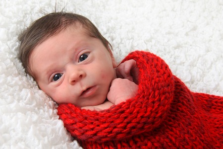 Newborn baby girl on a red knitted blanket. 