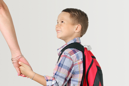 Young boy wearing a backpack holding mom's hand. Back to school concept.の写真素材