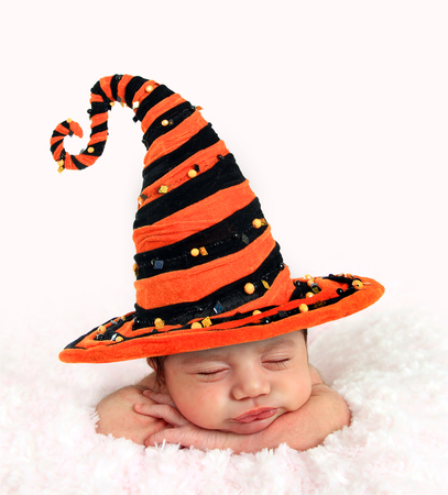 Newborn baby girl wearing a Halloween witch hat.の写真素材