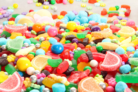 Assorted variety of sweet sugar candies includes lollipops, gummy bears, gum balls and sugar fruit slices. Kids birthday party background.の写真素材
