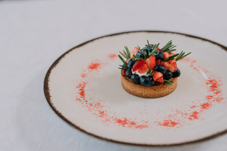 Delicious tartlet with strawberries and blueberries on a white plate