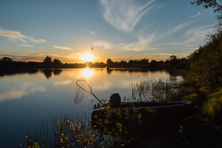 Fisherman in a boat on the lake at sunset with a fishing netの写真素材