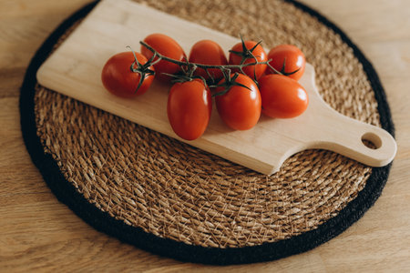 Cherry tomatoes on a wooden cutting board on a wicker backgroundの写真素材