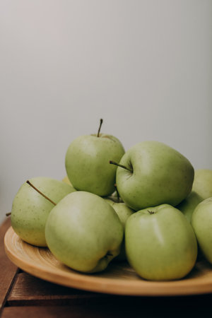 Green apples in a wooden plate on a wooden table. Selective focus.の写真素材