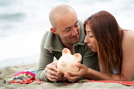 Budget holidays - young couple holding a piggy bankの写真素材