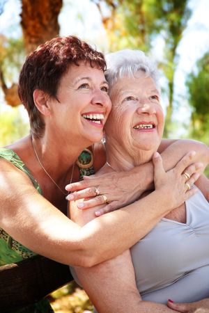beautiful senior mother and daughter hugging and looking upの写真素材