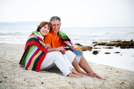 Happy mature couple sitting on the beach. の写真素材