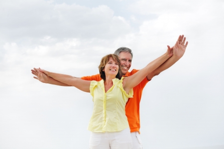 Happy mature couple standing with arms outstretched. の写真素材