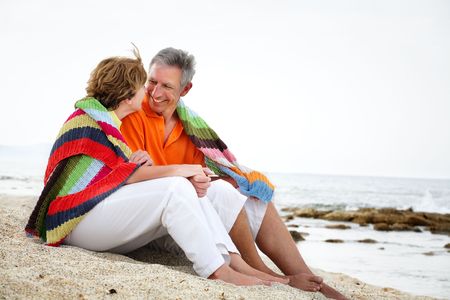 Happy mature couple sitting on the beach. の写真素材