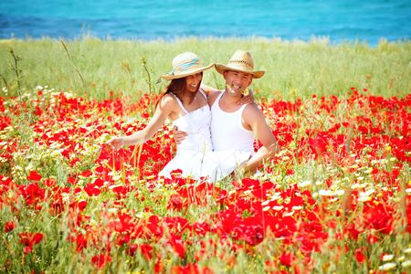 Young happy couple on a meadow full of poppies.の写真素材