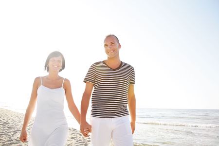 Happy young couple taking a walk on the beach. の写真素材