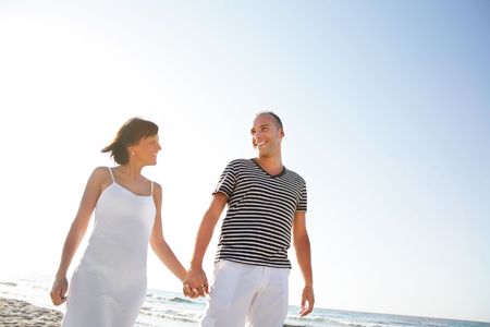 Happy young couple taking a walk on the beach. の写真素材