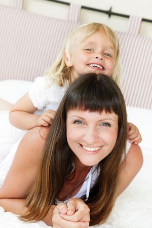 Mother and daughter posing happily in bed. Shallow DoF. Focus on mother. の写真素材