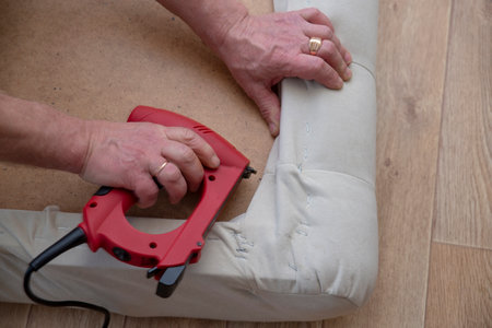 Working with a stapler. Handmade. Repairing furniture. Diy. Restoring the sofaの写真素材