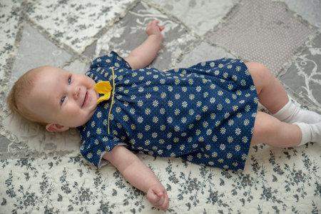 A little girl is lying on a veil. Blue dress in chamomile.の写真素材