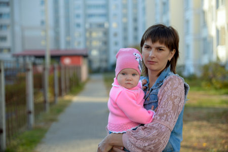 A mom plays with her baby in the yard near the house in the fallの写真素材
