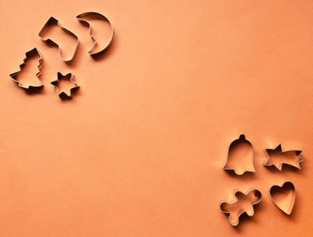 Christmas cake molds in a shape of moon, Christmas tree, sock, bell, heart, falling star, star and gingerbread man on a cinnamon color background.  Minimal new year concept.の写真素材