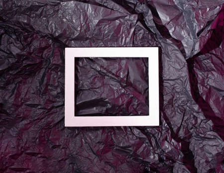 White picture frame on crumpled black and pink neon background. Creative flat lay concept.の写真素材