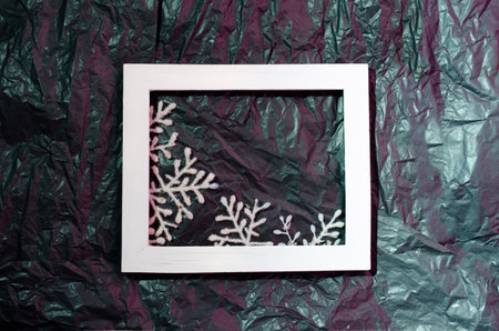 Snowflake in a white picture frame on a neon black and pink background. Minimal flat lay composition.の写真素材
