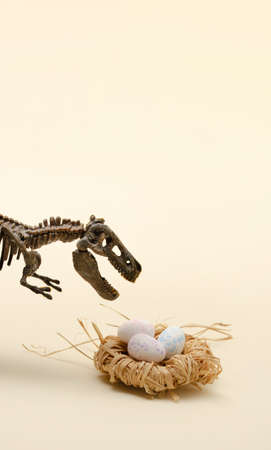 Easter composition with T-Rex and eggs in a nest. Dinosaur world on a beige background.の写真素材