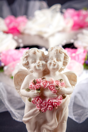Two angels holding a heart made of flowersの写真素材