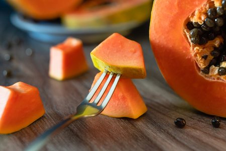 Papaya, papaya on a plate , slices of papaya on a fork on a wooden tableの写真素材