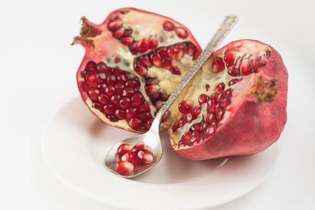Pieces of Pomegranate and Pomegranate seeds on white plate with white backgroundの写真素材