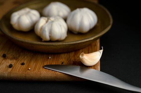 Garlic and knife on wooden board