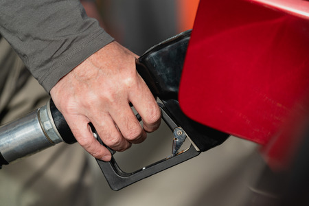 Close Up of Human Hand Holding a Fuel Pump Nozzle Filling Up the Car Tank