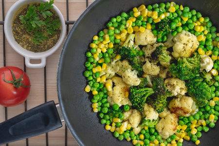 Roasted Vegetables on a Frying Pan. Cauliflower, Broccoli, Green Peas, Corn, Tomatoes Close Up, Top Viewの写真素材