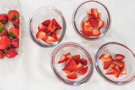 Sliced Strawberries in Clear Glass Bowls, Top View on White Backgroundの写真素材