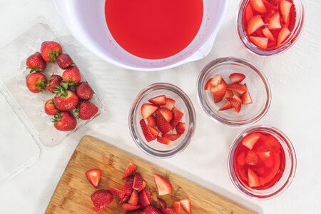 Strawberry Jelly with Slices of Strawberry in a Glass Bowls, Berries on a Kitchen Table, Close up on White Background. Fresh Light Dessert, Berry Mousseの写真素材