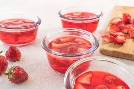 Strawberry Jelly with Slices of Strawberry in a Glass Bowls, Berries on a Kitchen Table, Close up on White Background. Fresh Light Dessert, Berry Mousseの写真素材