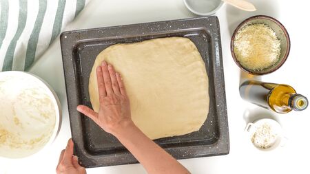 Baking cheese bread step by step. Woman gently unfurl dough onto prepared backing sheet. Close up, top view, on white background.の写真素材