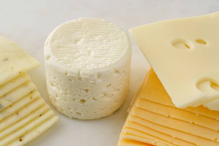Variety of cheese close up. Brie, or camembert, pepper jack, gouda, and swiss cheese sliced on a marble serving board.の写真素材
