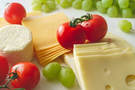 Variety of cheese served with tomatoes and green grape. Appetizer conceptの写真素材