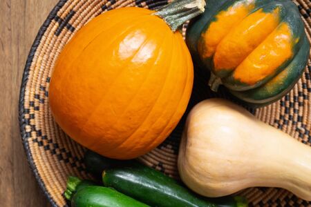 Squash family. Fresh, organic acorn squash, butternut squash, and pumpkin close up on a wooden background, top viewの写真素材