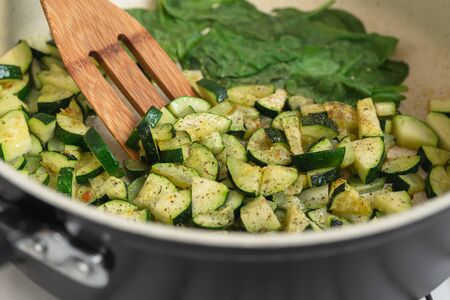 Zucchini and spinach. Roasted sliced zucchini and spinach with some seasoning on a frying pan close upの写真素材