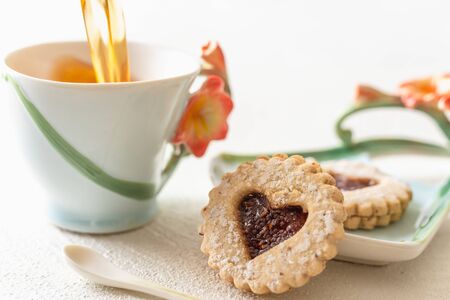 Heart shaped cookies and cup of tea close up on white background. Romantic, Happy Valentine's Day conceptの写真素材