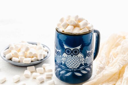 Marshmallow and coffee. Owl-shaped ceramic mug with marshmallows close up on white background, copy spaceの写真素材